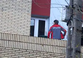 Un ertzaina inspecciona el cristal de la ventana por donde entró el disparo en la casa de la vecina de Deba.