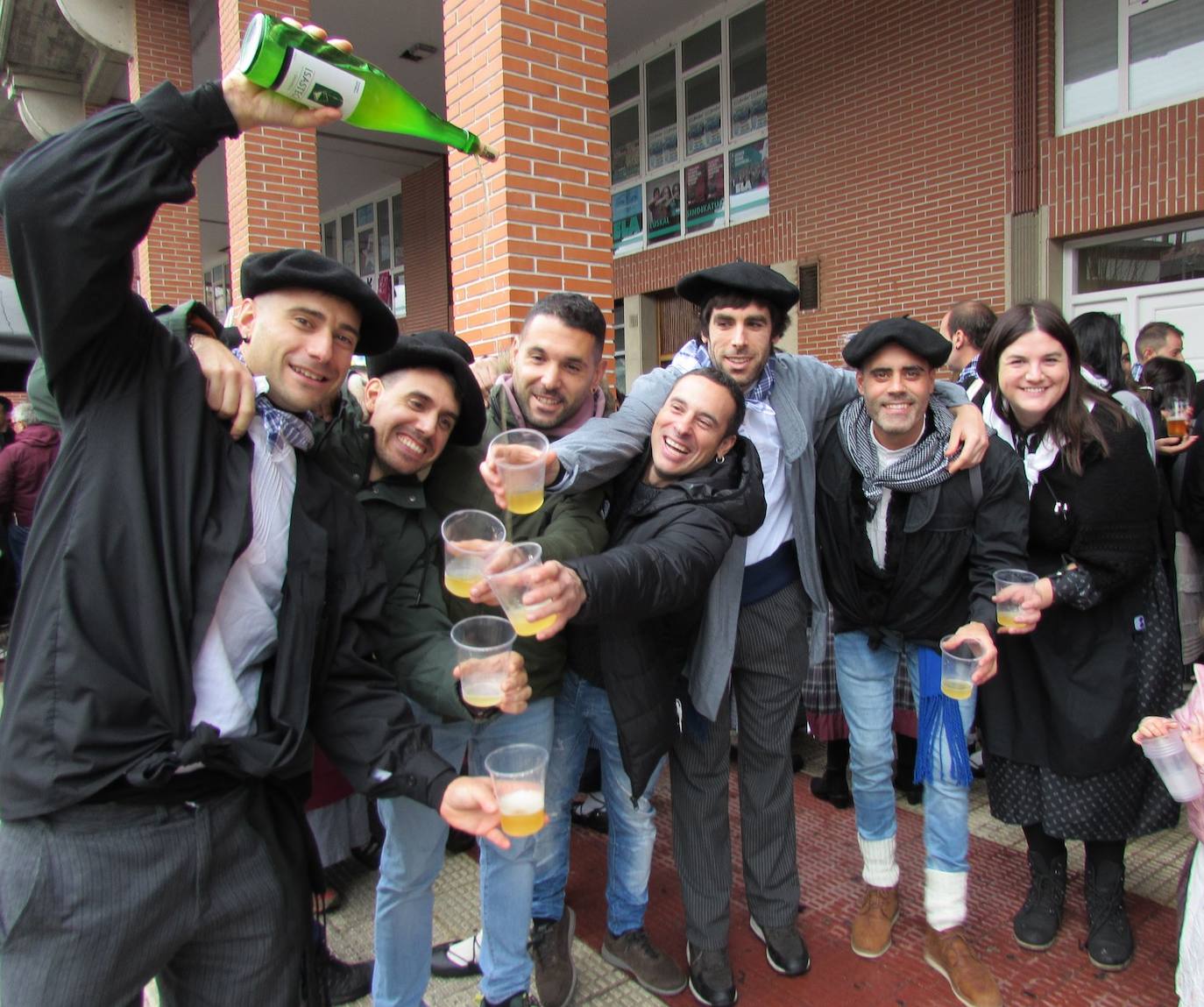 Imagen principal - Arriba, una cuadrilla tomando un trago de sidra en la calle. Muchos consumidores realizaron sus compras navideñas en los puestos de alimentación instalados en la plaza Biteri. Debajo, niños comiendo talo con txistorra