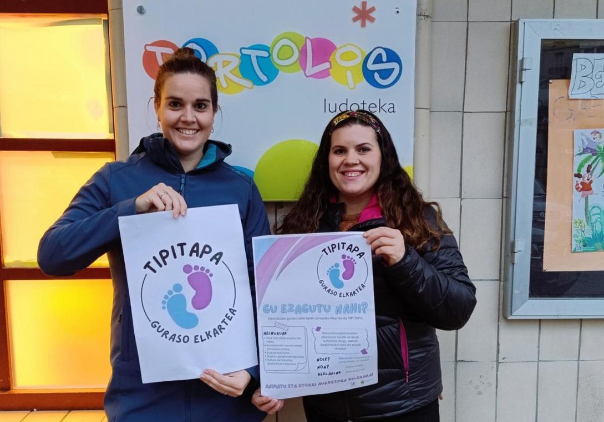 Dos de las madres impulsoras de la recién constituida asociación de padres y madres TipiTapa muestran los carteles de su presentación.