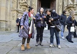 Tres turistas comprueban en sus móviles, tras visitar la iglesia de Santa María, la siguiente parada en su ruta por Donostia.