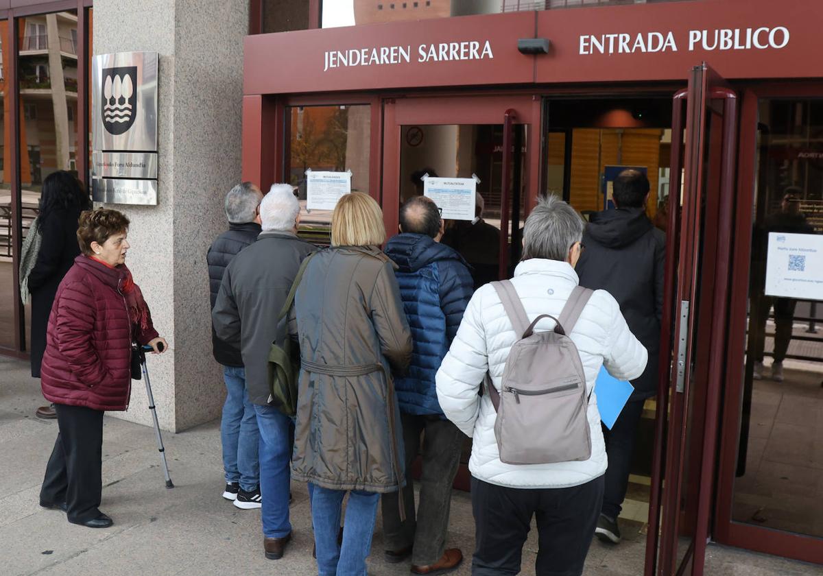 Jubilados y otros usuarios contemplan el cartel informativo sobre el error en el IRPF a las puertas de Hacienda en Donostia.