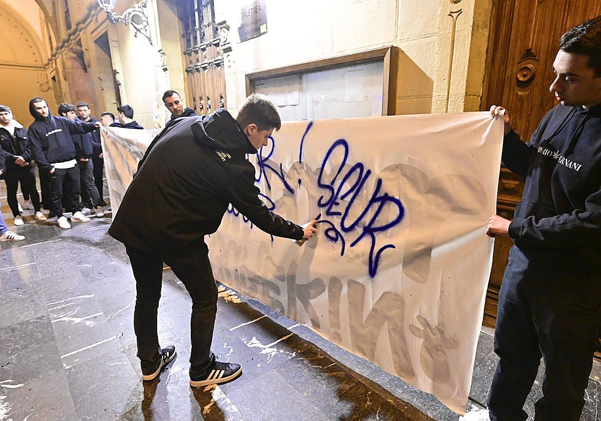 Un chico firma en una pancarta con el nombre de 'Seur', el sello con el que Lukas rubricaba sus grafitis.