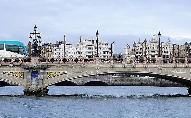 Imagen principal - Vista del puente María Cristina desde el barco, la familia de Ucrania compuesta por Valentina, Irina y Daniel, y la rueda de molino incrustada en el muro que está junto a la subida al campus de Deusto. 