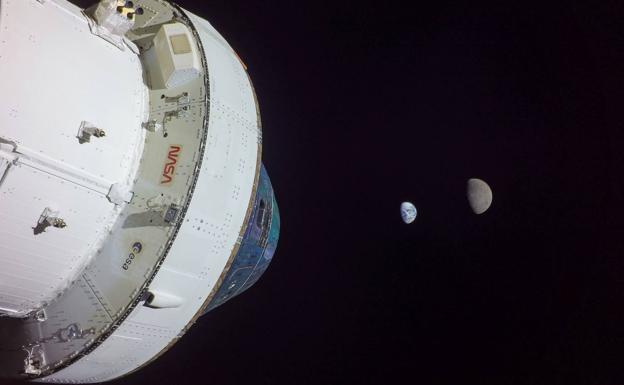 Imagen tomada desde la cámara en una de las alas de la nave espacial Orión de la NASA en la que se aprecian, al fondo, la Tierra y la Luna. 