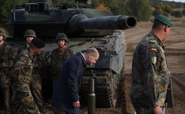 Olaf Scholz baja la cabeza al pasar delante de un tanque Leopard 2 durante un ejercicio en Ostenholz. 