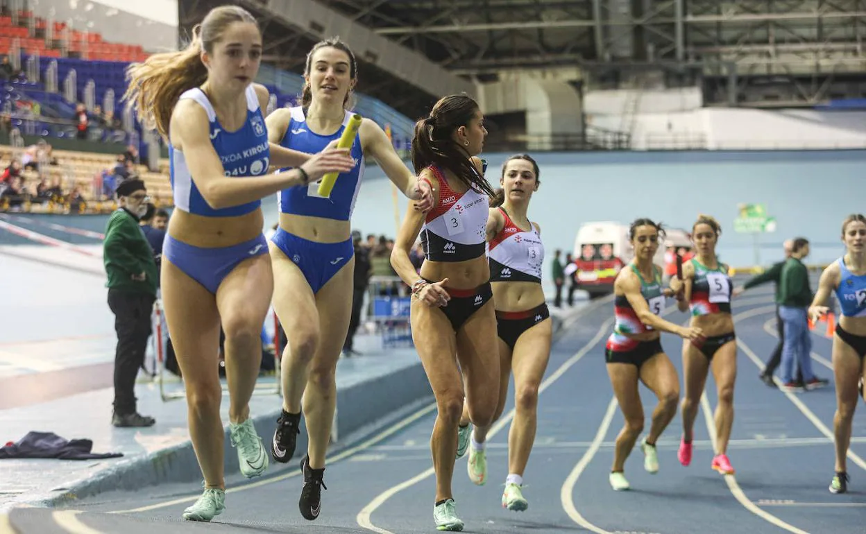 Atletas del Atlético y del BAT entregan los testigos a sus compañeras en el relevo 4x200. 