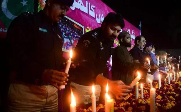 Police officers and residents light candles to pay tribute to the victims of the Peshawar mosque suicide attack