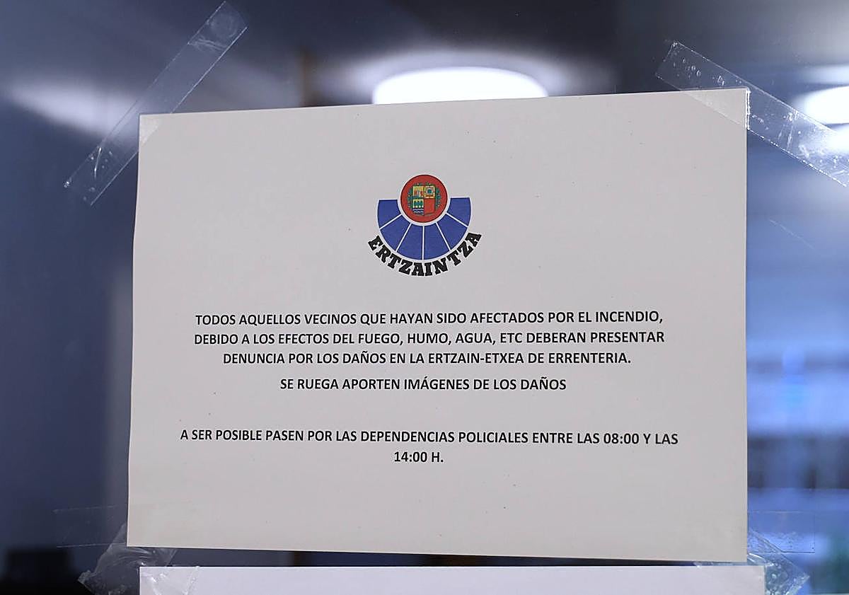 Imagen principal - Cartel de la Ertzaintza pidiendo a los vecinos afectados que denuncien. Dos vecinos evaluaban ayer los daños provocados por el fuego.. La viviend afectada por el incendio.