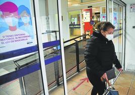 Una mujer con mascarilla sale ayer del centro de salud de Eibar, donde hay carteles que recomiendan el uso de los cubrebocas.