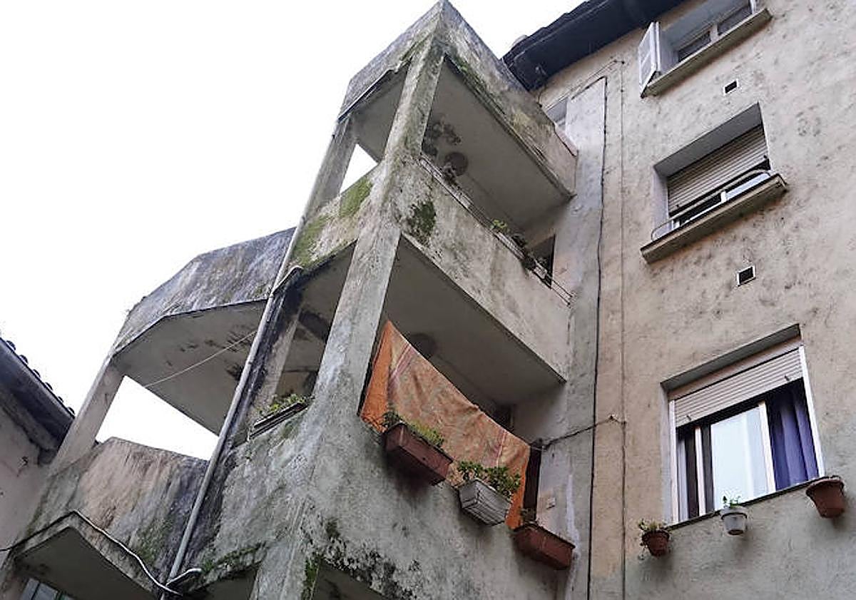 Imagen principal - Imagen de la escalera de la que se accede a las tres viviendas superiores de la casa de la calle Matxaria. Una de las habitaciones del piso y el portal del edificio.