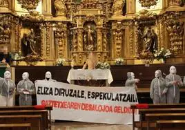 Una pancarta frente al altar donde se puede leer 'Iglesia avariciosa, especuladora!'.