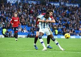David García sujeta por detrás a Sadiq mientras intenta controlar un balón.