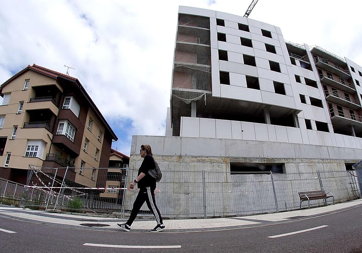 Una mujer pasa ante un bloque de viviendas en construcción en el barrio donostiarra de Txomin.