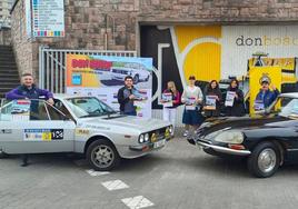 Los organizadores y vehículos posan con el cartel frente al centro formativo.