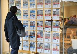 Un joven mira el escaparate de una inmobiliaria