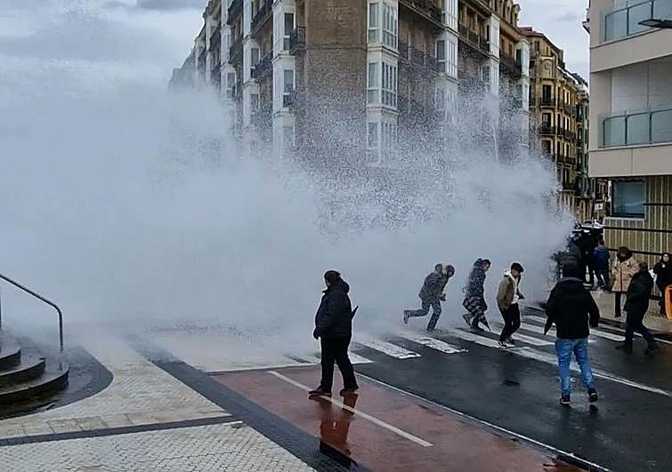 Momento en el que una ola coge por sorpresa a varias personas en el Paseo Salamanca de Donostia.