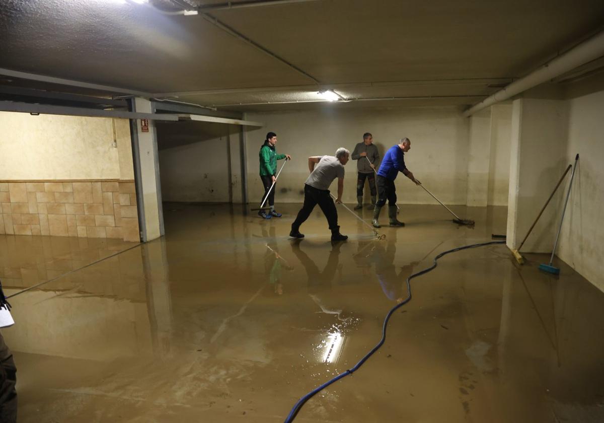 Varios vecinos se afanan con los cepillos para terminar de evacuar todo lo que entró en sus garajes de Amasa-Villabona, en los que el martes tres bombas de achique no pudieron evitar que se acumularan 80 centímetros de agua.