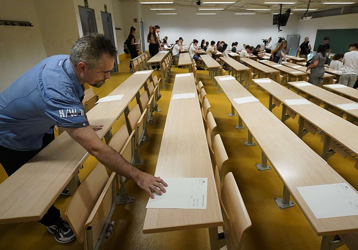Un docente reparte unos exámenes en un aula de la UPV.