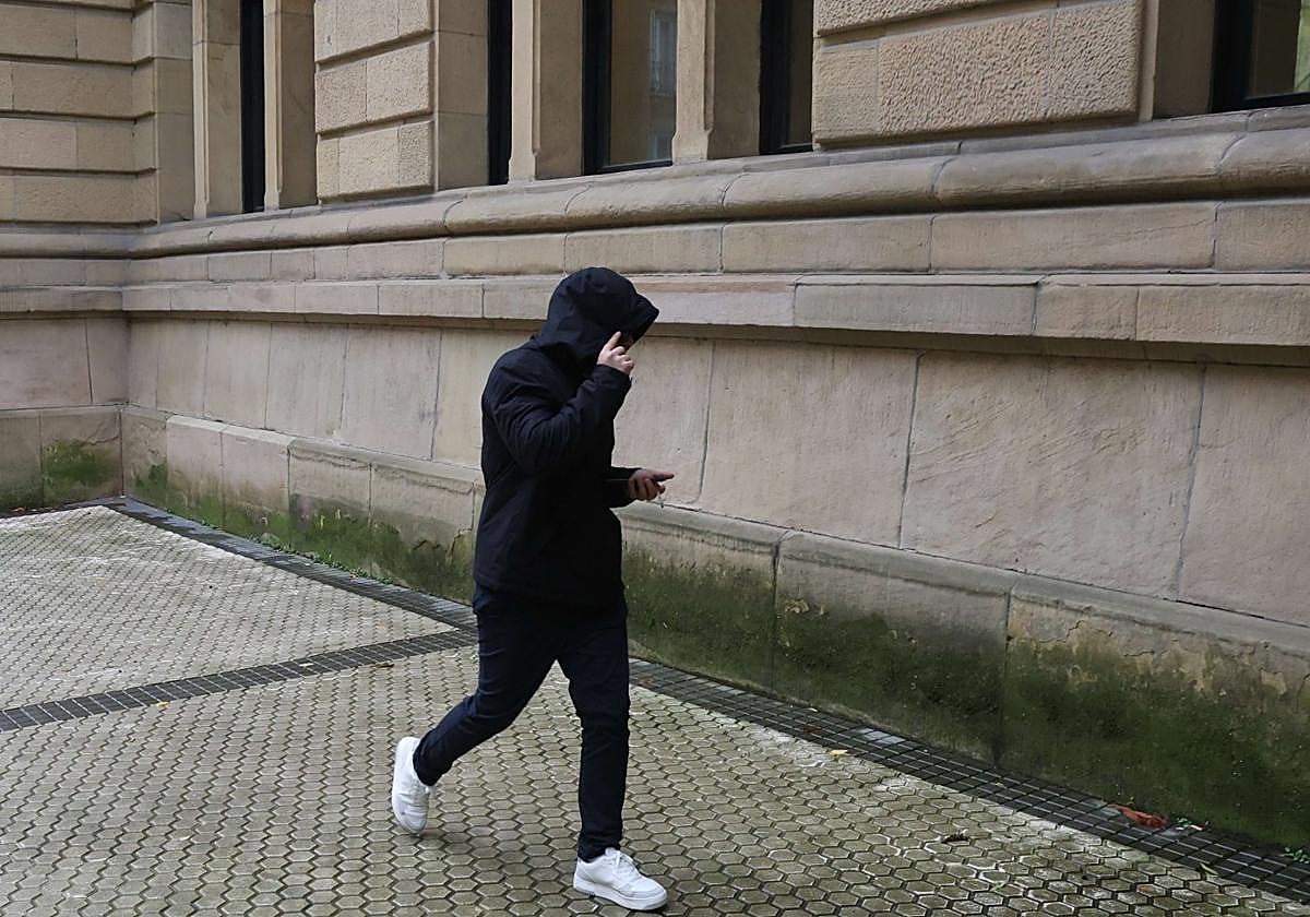 Uno de los acusados por la muerte de Santi Coca se cubre el rostro con la capucha, en el camino a una de las sesiones del juicio celebrado en la Audiencia de Gipuzkoa.