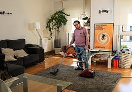 Jorge Correa pasa el aspirador en el salón de su casa en Donostia.
