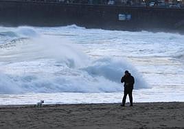 Un hombre pasea a su perro en la playa de Zurriola, en Donostia.