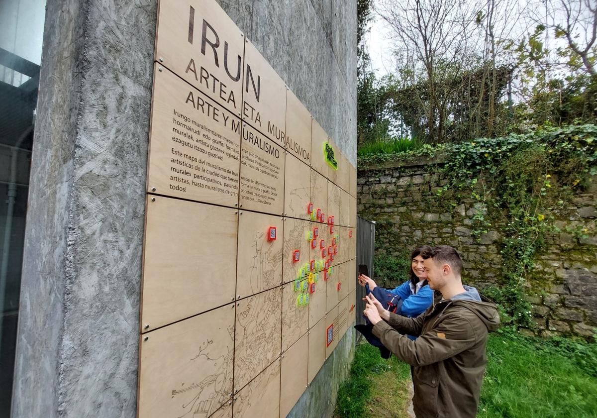 La delegada de Cultura, Nuria Alzaga, y el de Juventud, Sergio Javier, probaron los códigos QR del mapa interactivo del muralismo local que se ha colocado en el lateral del ascensor de Luis Mariano a Artaleku.