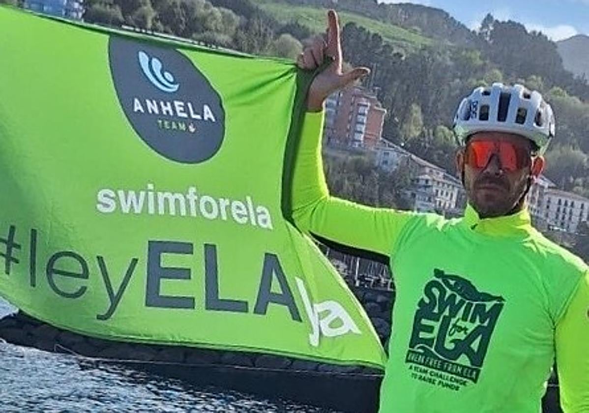 El ciclista ondarroarra Mikel Osa junto a una bandera que reivindica la ley de la ELA.