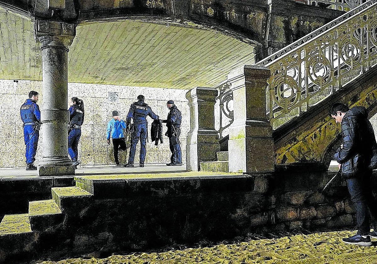 Varios agentes de la Ertzaintza cachean a un joven en los voladizos de la playa de La Concha.