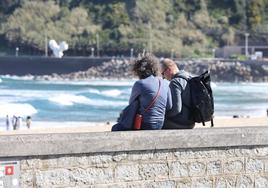 Una pareja disfruta del buen tiempo en el muro de la playa de la Zurriola.