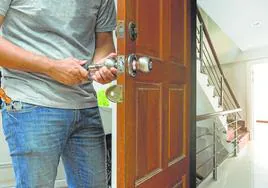 Un cerrajero cambia el bombín de la puerta de entrada de una vivienda.