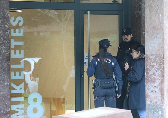 Agentes de la Ertzaintza conversan con una vecina en el portal de la vivienda donde han ocurrido los hechos.