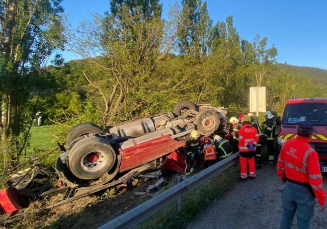 El camión ha quedado volcado fuera de la vía tras la colisión.