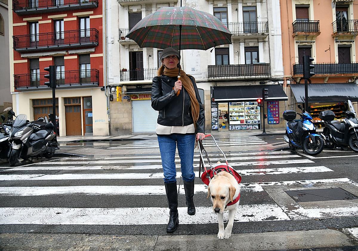 Miren termina de cruzar la calle agarrando a su perra guía, 'Rasca', por el arnés.