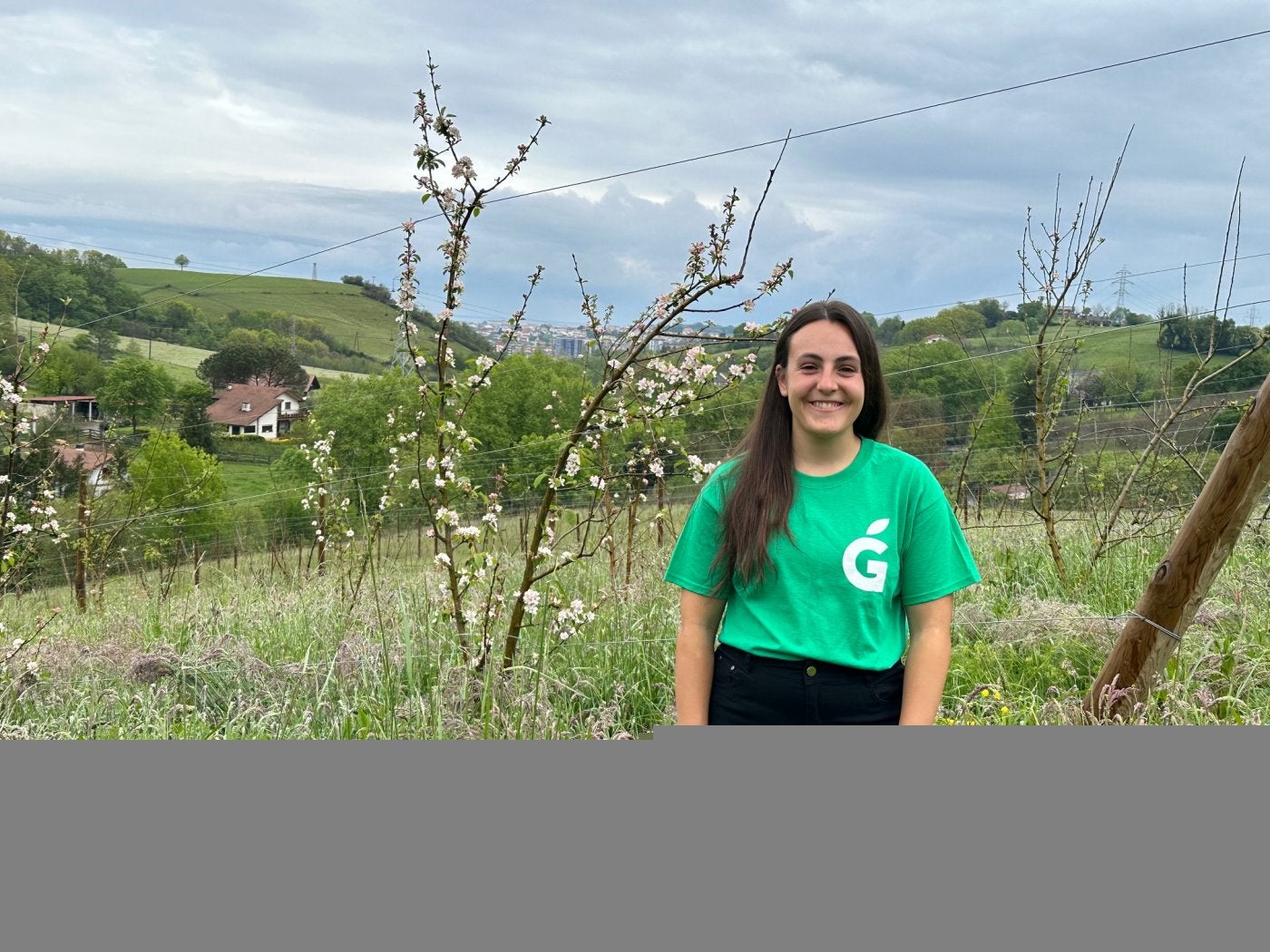 Oihana Recalde en Olaberria, entre sus manzanos, con Irun y la desembocadura del Bidasoa al fondo.