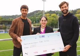 Xabi Prieto y Fernando Llorente posan con la donación junto a Nerea del Barrio, de Esku Hutsik.