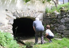 Un niño observa junto a su abuelo la parte inferior del histórico molino de Lastur.