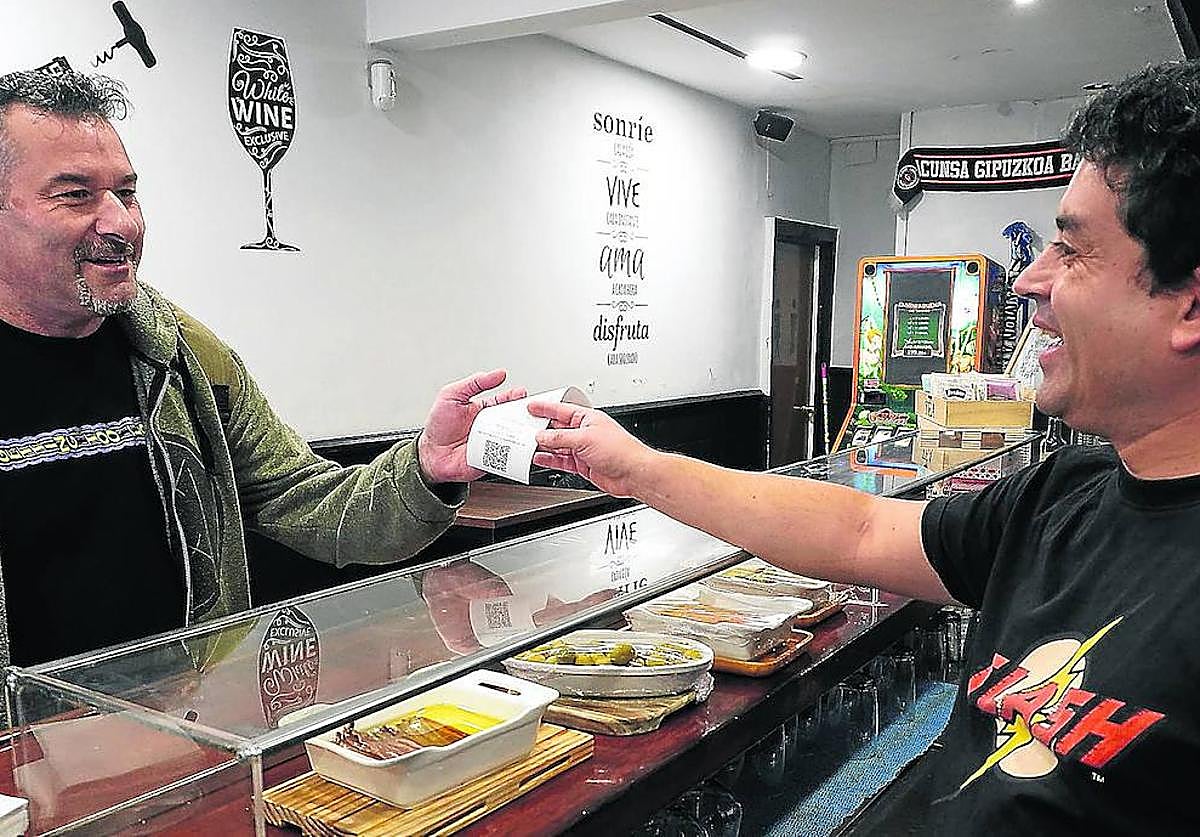 Un hostelero de Donostia entrega un TicketBai a un cliente.