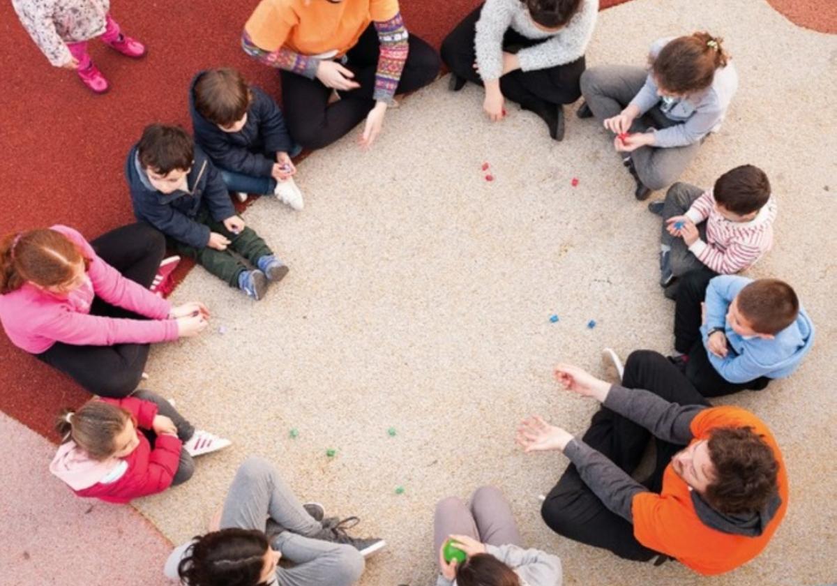 Niños y adultos forman un corro durante una sesión de juegos.