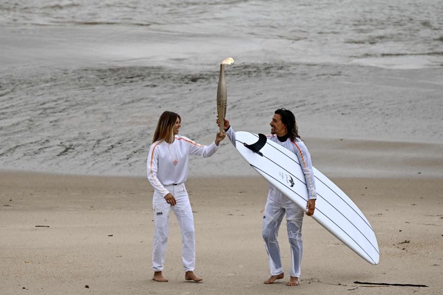 Los surfistas Zoe Grospiron y Edouard Delpero durante el relevo de la llama olímpica. 