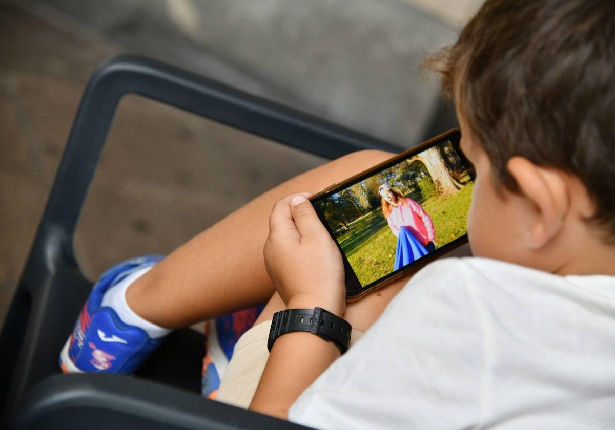 Un niño mira la pantalla de un teléfono móvil.