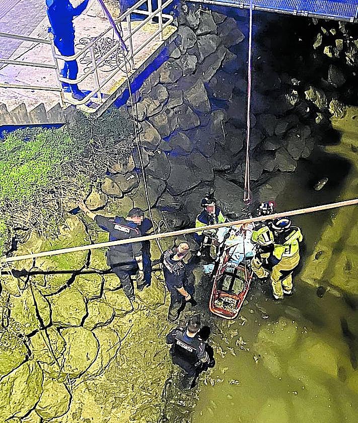 Imagen secundaria 2 - Imagen del rescate y tres tres agentes ante el lugar donde cayó el joven