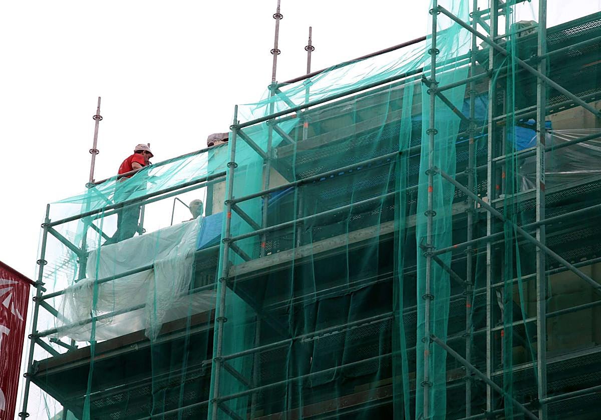 Dos operarios trabajan en la rehabilitación de una fachada en San Sebastián.
