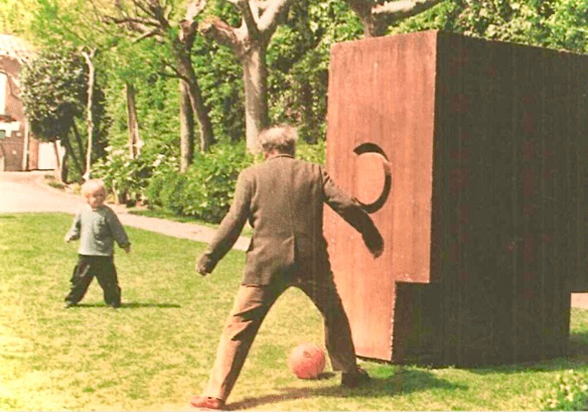 Eduardo Chillida juega a fútbol con un nieto, hijo de su hija Susana, junto a una de sus obras