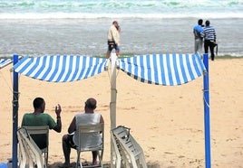 Dos hombres conversan bajo un toldo el primer día de la puesta en marcha del servicio en Donostia.