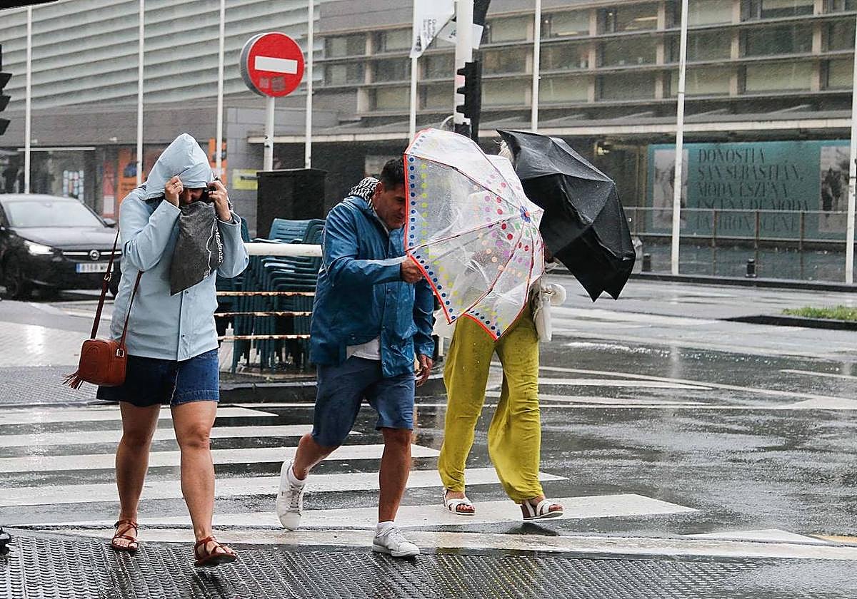 Unos turistas bajo la lluvia en Donostia.