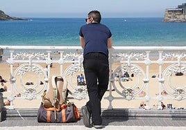 Un turista contempla la bahía donostiarra apoyado en la barandilla de La Concha.