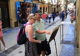Dos turistas leen la carta de un restaurante en la Parte Vieja donostiarra.