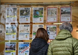 Una pareja mira el escaparate de una inmobiliaria en Donostia.
