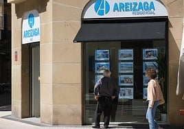 Viandantes observan anuncios de venta de casa en Donostia.