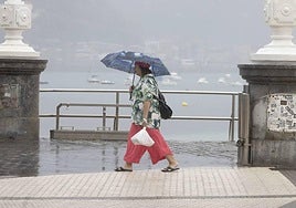 Una mujer caminando bajo la lluvia en Donostia.